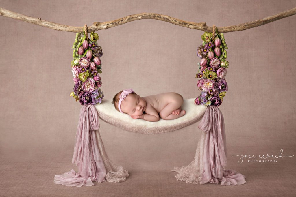 Newborn baby girl on a floral swing