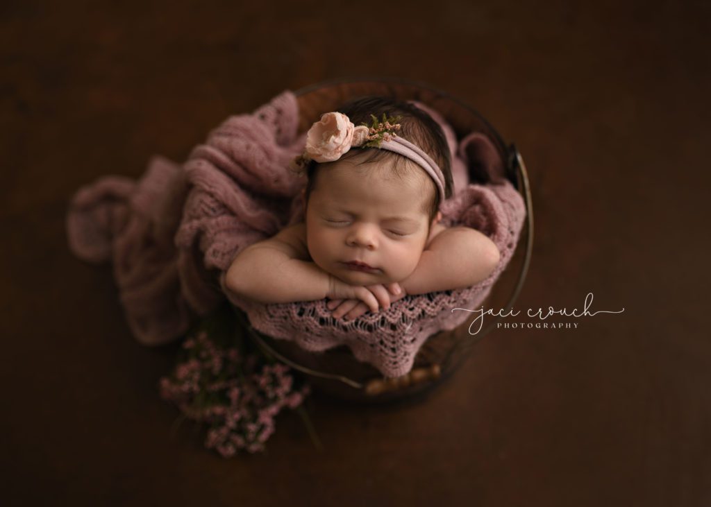 PRETTY NEWBORN GIRL IN A BUCKET WITH PINK FLOWERS
